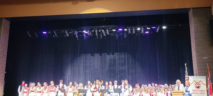 All the performers of the 50th-anniversary concert in Croatian folk costumes lined up across the stage, with the school banner beside the podium.