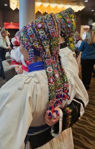 (English) Close-up from behind of an intricately beaded, multicolored folk headpiece.
