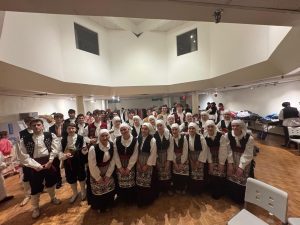Klub Stepinac in folk costumes posing for a group photo backstage before the performance.